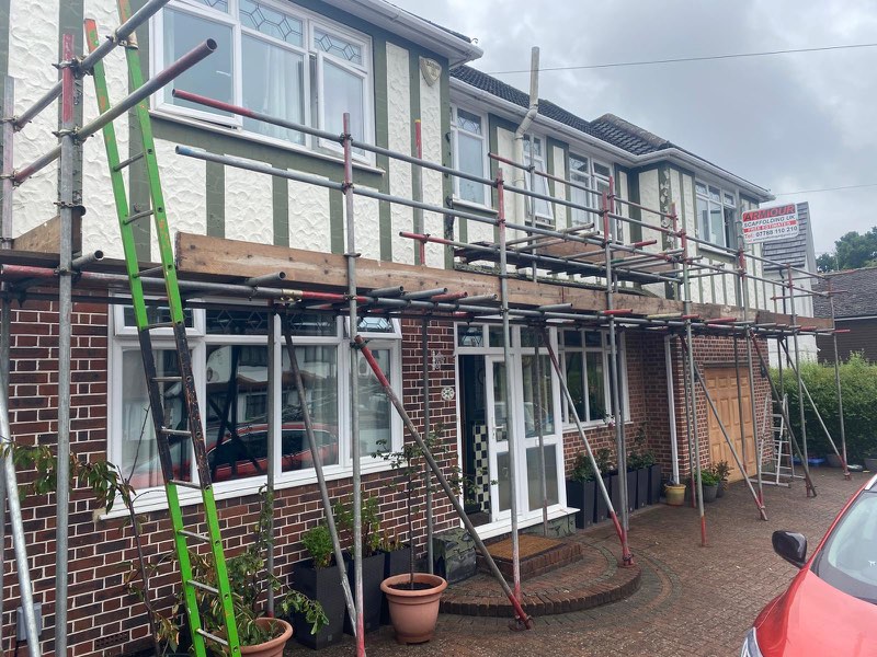 House front with scaffold across the first floor, over a porch and bay window