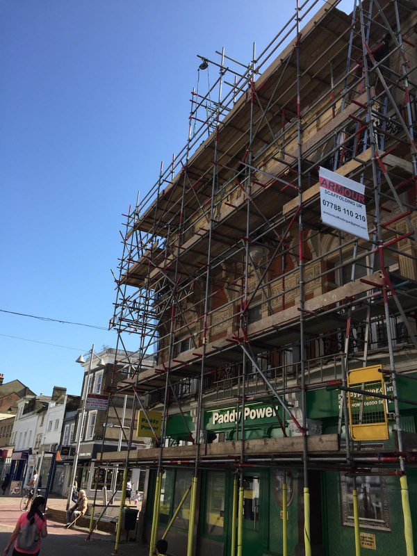 Large multi-lift scaffold across a corner high-street building above retail units